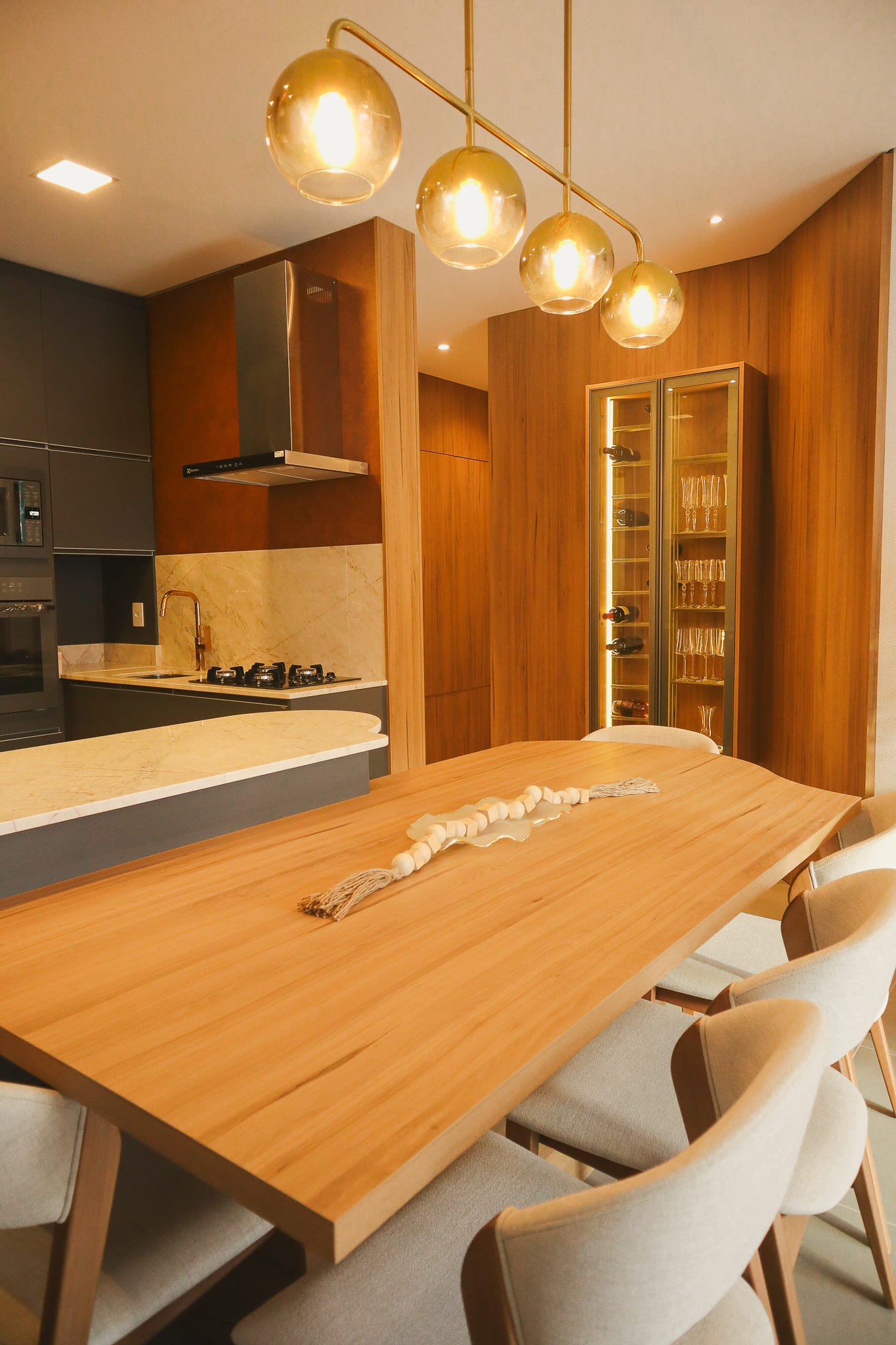 Cozinha AFETTO com bancada ilha integrada à mesa de jantar, mesclando minimalismo e design orgânico